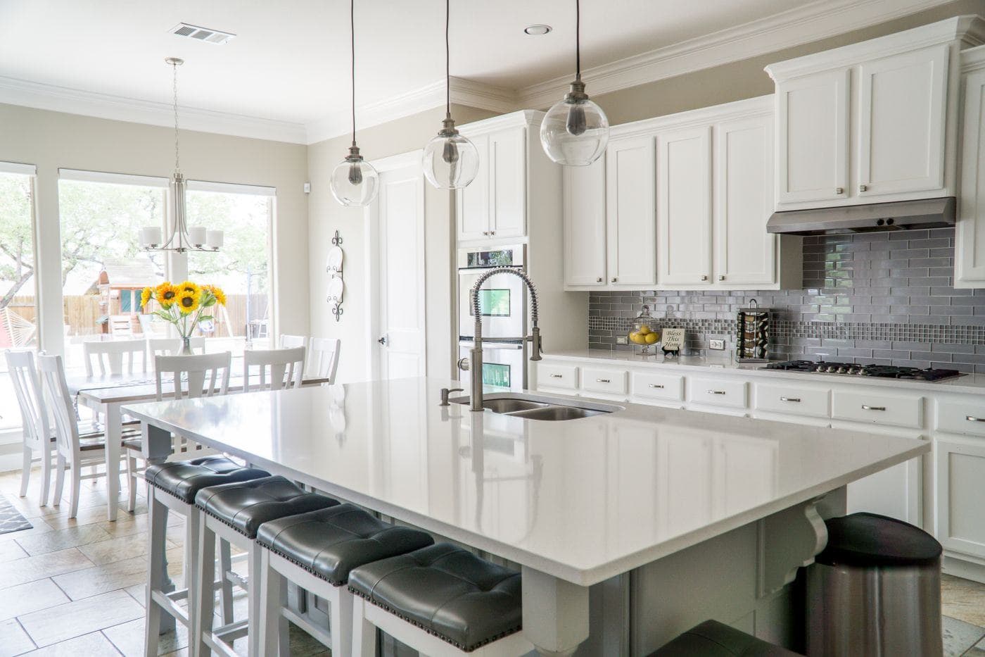A bright kitchen with a white island, clear counter tops and a dining area beyond